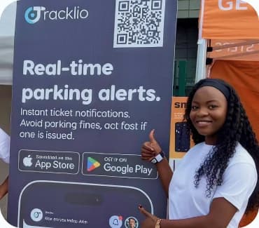 Three members of the Tracklio team in branded t-shirts beside a real-time parking alerts banner at an outdoor event